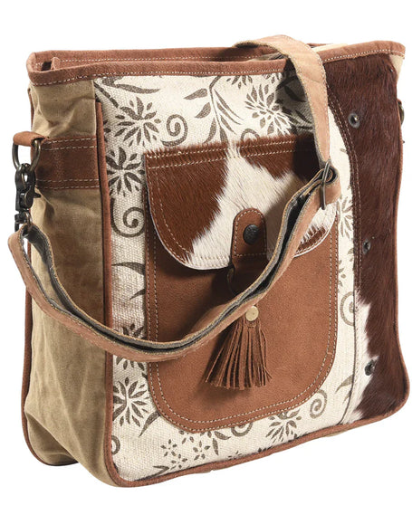 A beautiful  canvas messenger bag featuring a leather tassel and cow fur on the bag.