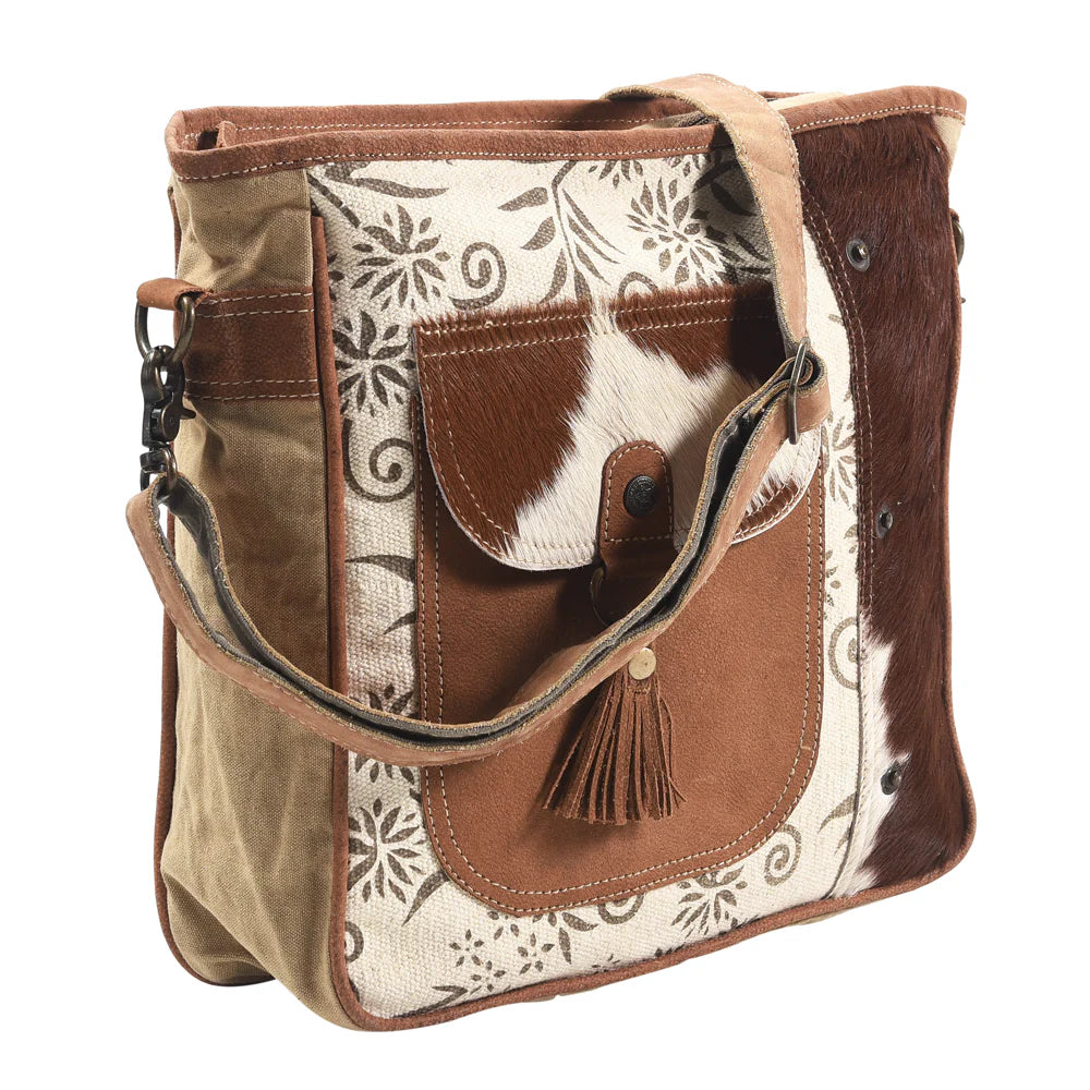 Brown and beige handbag with floral pattern on a white background