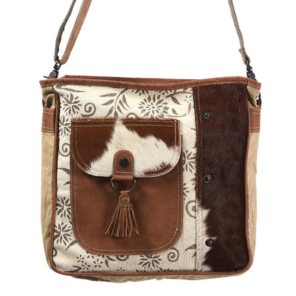 Brown and beige handbag with floral pattern and cowhide leather flap on a white background