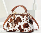 A brown and white cow print purse