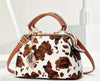 A brown and white cow print purse