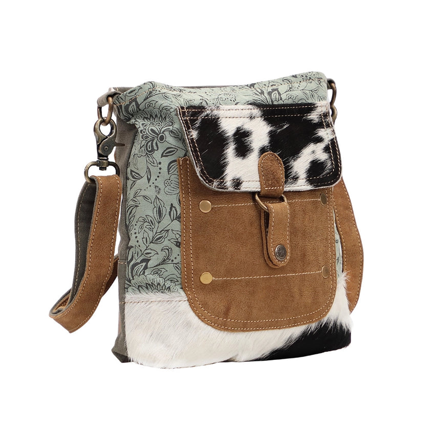 Handbag with cowhide pattern and floral design on a white background
