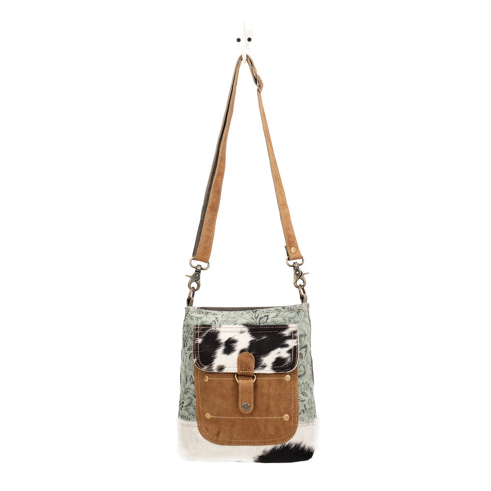 Crossbody bag with cowhide pattern on a white background