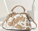 A tan and white cow print purse