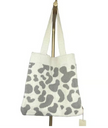 A large knit tote bag with a cow spotted pattern woven into it.