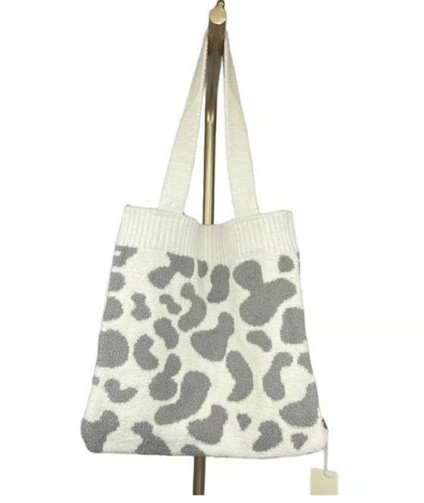 A large knit tote bag with a cow spotted pattern woven into it.