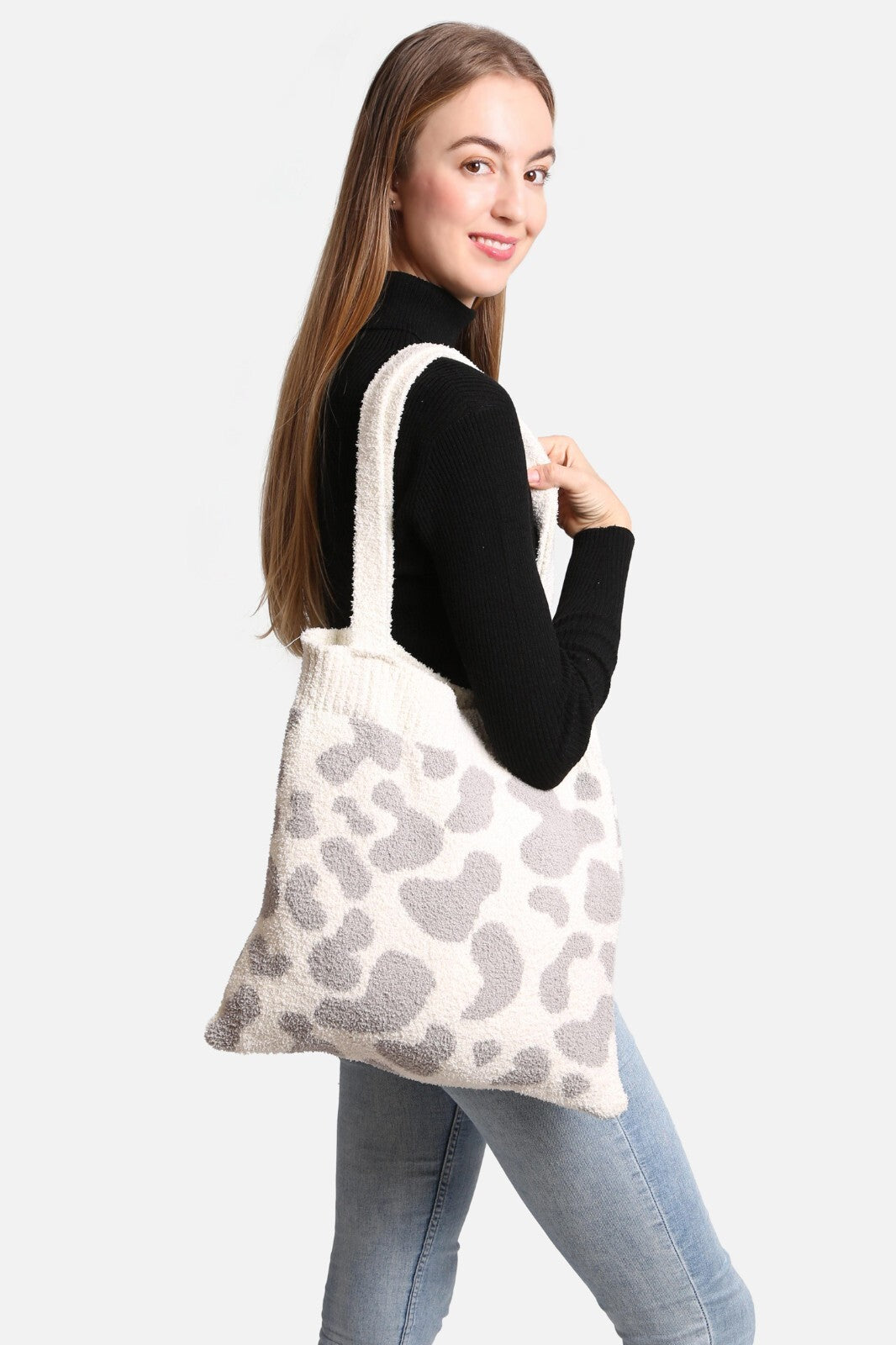 Image of a lady with the cow knit tote bag hanging from her shoulder.